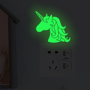 Luminous unicorn wall sticker glowing green on a modern white electrical wall switch