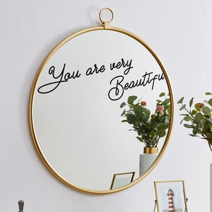 Detail of round gold frame mirror with You are very Beautiful inscription on glass