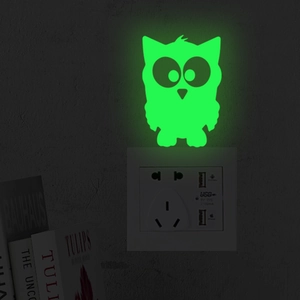 Luminous owl wall sticker glowing in dark above a power socket in a night bedroom
