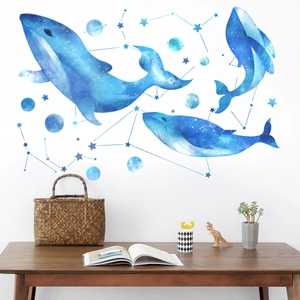 Blue watercolor whales and starry constellation wall decals applied to a white nursery wall