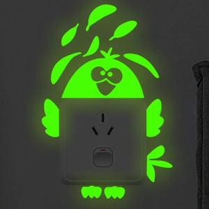 Luminous owl wall sticker glowing green around a power outlet in a dark room