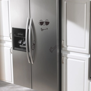 Black cartoon funny faces and cool stickers on a stainless steel double door refrigerator