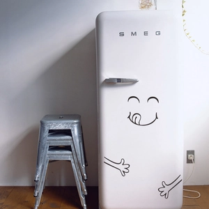 Macro shot of a funny tongue-out cartoon decal applied on a white vintage fridge door