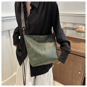 Detail view of dark green faux leather tote bag featuring ethnic embroidered wide strap