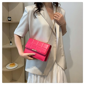 Detail of fuchsia quilted chain crossbody bag styled with an elegant white suit