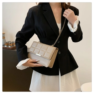 Detailed close-up of beige quilted crossbody bag with gold chain strap and metal buckle