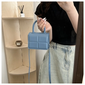 Detail of blue quilted PU leather mini handbag with top handle and crossbody strap