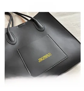 Gros plan sur un sac cabas noir avec cuir grainé et détails de poche boutonnée