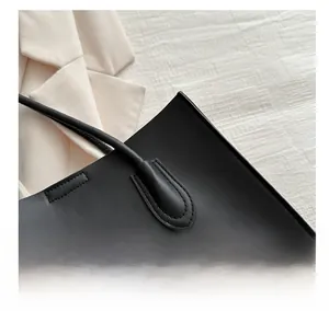 Gros plan sur les coutures robustes et les sangles renforcées d'un sac cabas en cuir PU noir