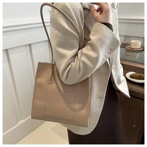 Détail du sac cabas beige avec lettrage doré et poche frontale sur texture cuir élégante
