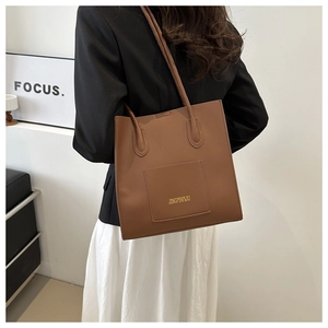 Détail d'un sac cabas en cuir marron avec poche extérieure et fines bretelles d'épaule
