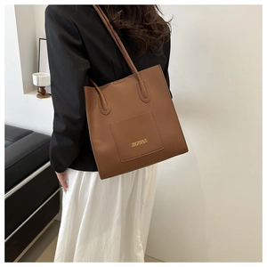 Détail du sac cabas en cuir PU marron avec logo doré et poche frontale fonctionnelle