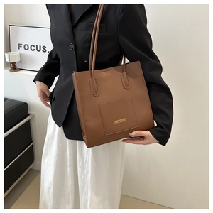 Détail d'un sac cabas marron avec poche frontale et fines lanières de transport