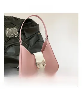 Detailed view of pink saddle bag with golden bow and elegant silver chain strap