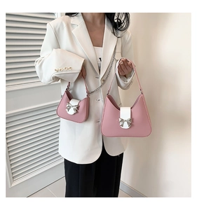 Detail of pink and white shoulder bags featuring silver metal bow accents and chain straps