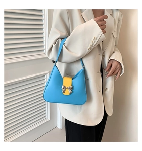 Detail of light blue leather shoulder bag with yellow strap and silver bow buckle
