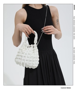 Detailed view of white quilted bubble shoulder bag with silver chain and drawstring closure