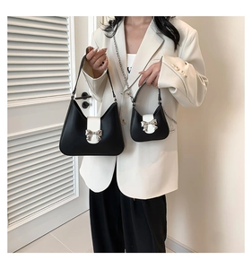 Detail of black and white handbag set with a silver bow clasp and mini chain bag accessory