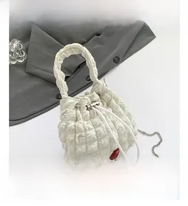 Detail of white bubble texture bucket bag with silver metal chain and drawstring closure