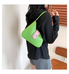 Detail of green faux leather shoulder bag with pink strap and silver bow decoration