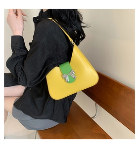 Detail of yellow crescent shoulder bag with green leather strap and silver bow buckle