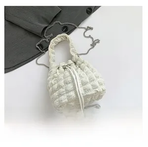 Detail view of white bubble texture bucket bag with drawstring closure and silver chain