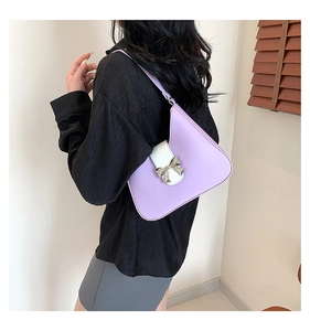 Detail of a purple and white leather shoulder bag with a silver metal bow buckle