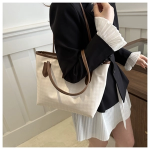 Close-up of a canvas tote bag with brown leather handles and spacious interior design
