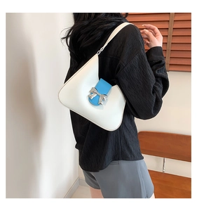 Detail of white saddle bag with blue strap and silver bow decoration on female model
