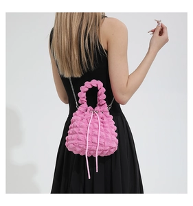 Close-up of pink bubble textured bucket bag with silver chain strap on black dress