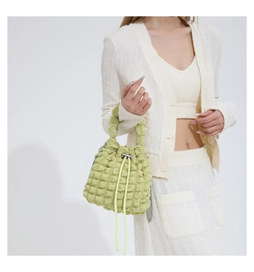 Close-up of light green popcorn textured bucket bag with elegant chain strap on shoulder