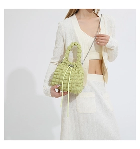 Close-up of light green popcorn textured drawstring bucket bag with silver chain strap
