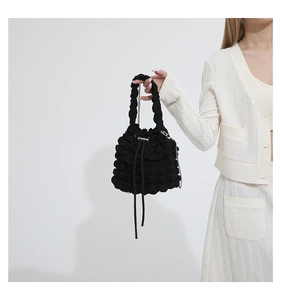 Close-up of black bubble textured bucket bag with silver chain and drawstring