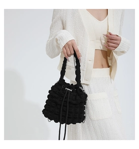Detail of black popcorn texture bucket bag with drawstring closure and chain strap