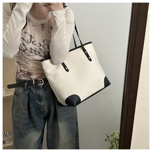 Fashionable oversized cream tote bag with black contrast trim shown in a mirror lifestyle view