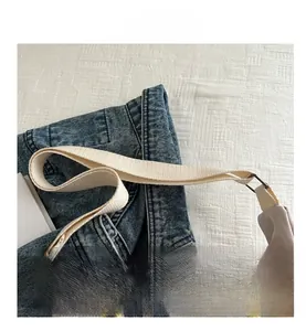 Detailed close-up of adjustable beige canvas strap and durable metal buckle on handbag
