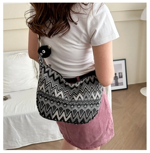 Détail d'un sac à bandoulière rayé ethnique avec un porte-clé pompon noir ludique