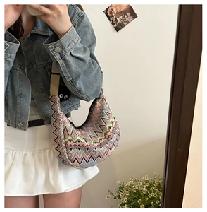 Détail du sac hobo en tricot coloré à motif zigzag avec bandoulière large et breloque chat