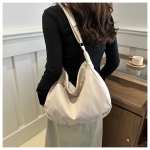 Rear view of a beige crescent tote bag showing its scale and soft draping on shoulder