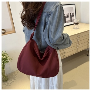 Deep burgundy nylon hobo bag shown from back view worn by a model in a minimal room