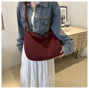 Burgundy crescent crossbody bag styled with a denim jacket and white pleated skirt