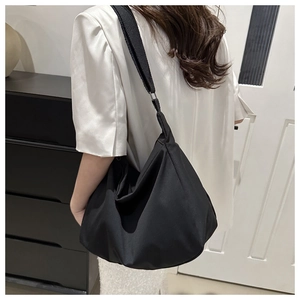 Detailed view of the large black minimalist dumpling bag with wide canvas shoulder strap