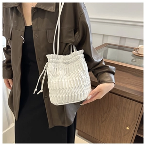 Detail of white pleated drawstring bucket bag with adjustable shoulder strap for women