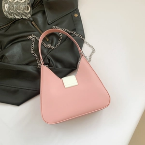 Minimalist pink and white leather handbag with silver chain detail on leather jacket background