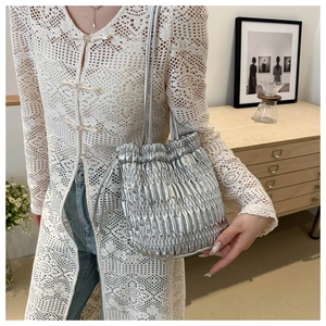 Silver pleated drawstring bucket bag featuring a metallic finish and a slender chain strap
