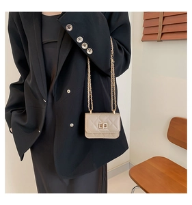 Detail of classic quilted texture and gold twist lock on beige mini crossbody bag
