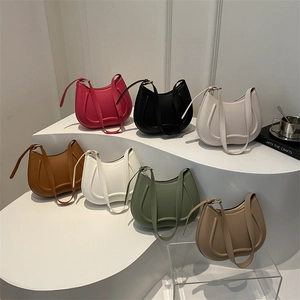 Minimalist half-moon underarm bags in seven trendy colors arranged on a white tiered display