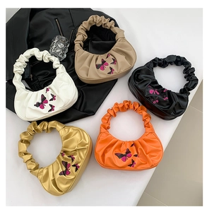 Detailed overhead view of five pleated cloud bags with butterfly embroidery in various colors