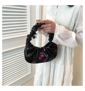 Detail of black pleated cloud bag with pink flower embroidery and textured handle