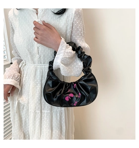 Detail of ruched handle and pink butterfly print on a black crescent shoulder bag